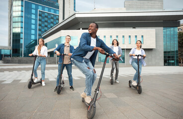 Five excited friends having ride on motorized kick scooters