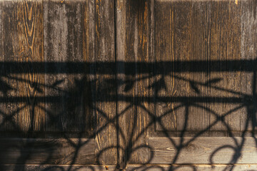 Ancient Weathered Wooden Doors with Shadow of Ornate Iron Fence