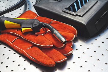 MIG/MAG welding gun,leather gloves and welding mask on metal desk
