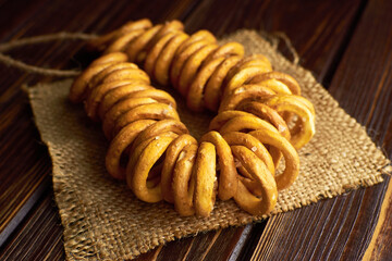 Small wheat bagels on a rope on burlap cloth on dark wooden table. Traditional russian food.