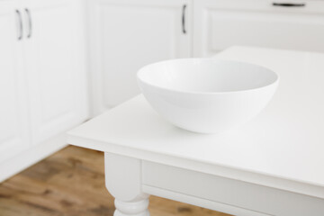 Fototapeta na wymiar Empty white bowl for salad on white table on background of kitchen. Minimalism.