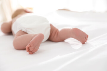 Obraz na płótnie Canvas Cute little baby in diaper on bed at home, closeup