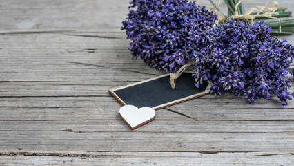Close up of bouguet of violet purple lavendula lavender flowers herbs with empty wooden pendant and wooden heart, on old rustic wooden table, wood background