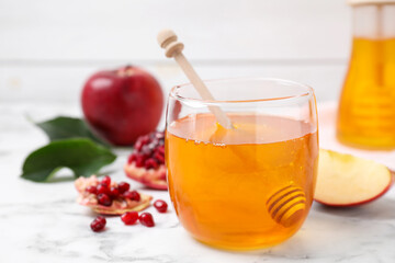 Honey, apples and pomegranate on white marble table, closeup. Rosh Hashanah holiday