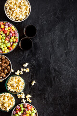 Set of flavored popcorn and soda on black table from above copy space