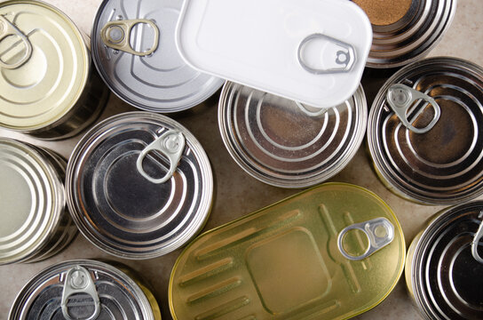 Flat lay view at various canned foods in tin cans on kitchen table, non-perishable, long shelf life food for survival in emergency conditions concept