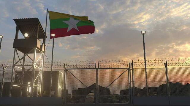 Waving flag of Myanmar above military base in the evening