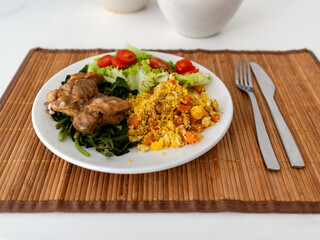 White crockery dish, with lettuce, tomato, broccoli, Moroccan couscous and oven-roasted chicken file, on straw base on white table, Rio de Janeiro, Brazil