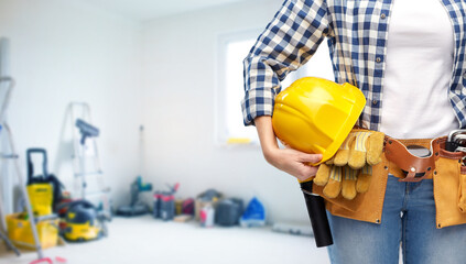 repair, construction and building concept - close up of woman or builder with helmet and working tools on belt over utility room background