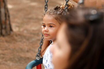 ritratto stretto di una bambina scura di carnagione di origine brasiliana che gioca su un altalena