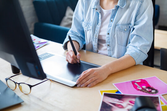 Close Up Portrait Of Graphic Designer Hands Retouching Images Using Graphic Drawing Tablet In Special Program. Laptop,monitor, And Color Palette. Retoucher Workplace In Photo Studio. Creative Agency.