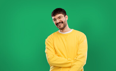 people concept - smiling young man in glasses and yellow sweatshirt over emerald green background