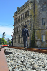 Fototapeta premium Back view of a man walking on the railway road at Oamaru old town.