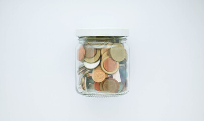glass jar with coins on white background, save money