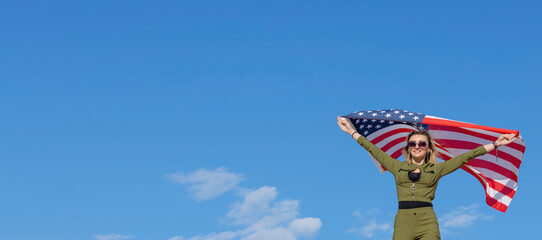Woman with USA flag against blue sky background. Freedom concept. America Independence Day.