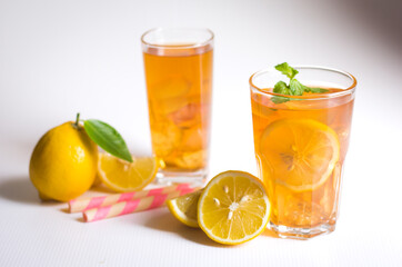 Glasses of ice tea with lemon slices and mint on white background