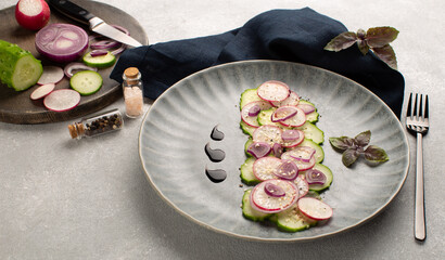 Fresh salad with radish.cucumber,red onion,sesame seeds and purple basil leaf in grey ceramic plate...