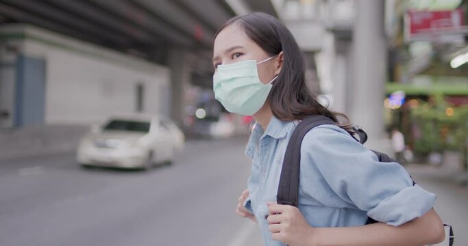 Thai Asian woman wearing mask waiting bus and friend on road, protect corona virus or Covid19 and problem of air pollution