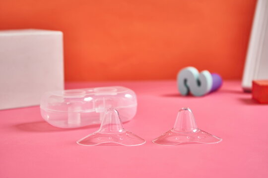 A pair of silicone nipple protectors in a pink background