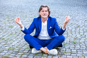 Fototapeta na wymiar businessman in his 50s sitting on sidewalk and meditating