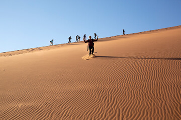 Fototapeta na wymiar Mujer tirándose por la duna 45 en el desierto de Sossusvlei, Namibia-