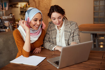 Business. Colleagues Meeting In Cafe. Diversity Ethnic Women Working On Laptop. Smiling Brunette Showing Something At Screen.
