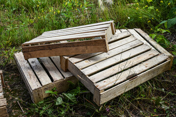 Fototapeta premium Old wooden crates lie on the grass. Three empty vegetable crates stacked on top of each other. 