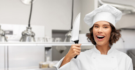 cooking, culinary and people concept - happy smiling female chef in toque with knife over restaurant kitchen background