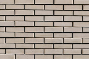 Beige brick wall with gray decorative tile seams for wall decoration. Smooth beige facing brick. Background, texture