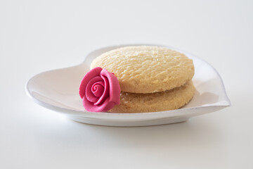 Cookies on white plate. Plate heart shaped. butter biscuits on white background. cookie and rose