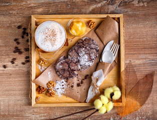 Cinnamon coffee, orange jam and homemade chocolate chip cookies. Dessert lies on kraft paper and coffee in paper cup.