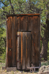 old wooden outhouse in the woods