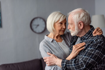 senior woman hugging husband, sick on dementia, while standing face to face