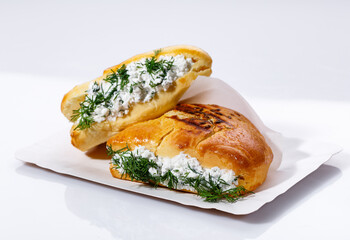 Fragrant muffin stuffed with cottage cheese and dill on a paper plate on a white background.