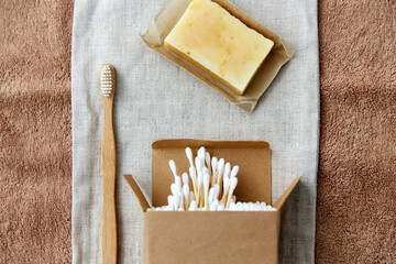 natural cosmetics, sustainability and eco living concept - wooden toothbrush, handmade soap cotton swabs on canvas