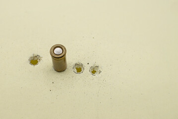 Four bullet holes in yellow cardboard with an embedded 6.35 caliber bullet and traces of powder