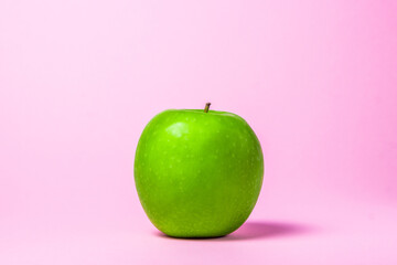 Green apple on a pink background. Glamor apple