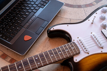 electric guitar next to a laptop with a pick online guitar lessons
