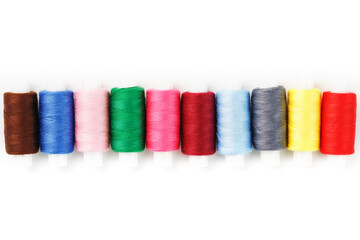 Colorful cotton craft sewing threads multicolored in a row isolated on a white background.