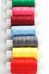 Colorful cotton craft sewing threads multicolored in a row isolated on a white background.