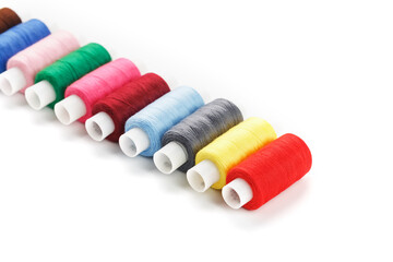 Colorful cotton craft sewing threads multicolored in a row isolated on a white background.