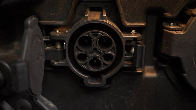 Connecting a charging gun to a car using the SAE J1772 charging port located on the side of the vehicle. Closeup shot