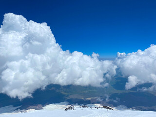 Blue sky and mighty white clouds. A breathtaking view from the top of Elbrus..