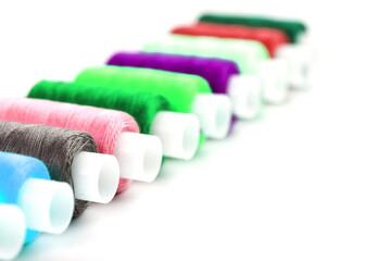 Colorful cotton craft sewing threads multicolored in a row isolated on a white background.
