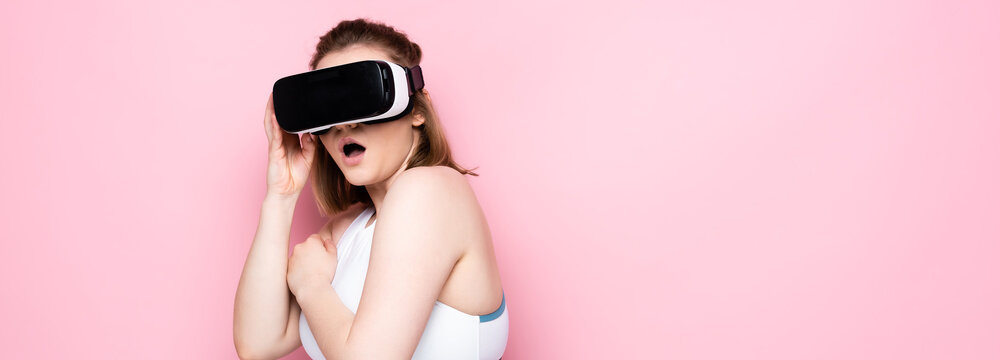 horizontal image of scared overweight girl in vr headset and sportswear on pink
