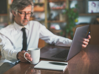 cup of coffee in the foreground next to a notebook and a pencil, scene of a businessman working from home smartly, blurred background