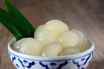 Longan in syrup and pandan leaf on wooden background. Traditional thai dessert.