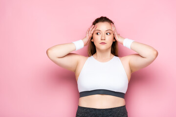 shocked overweight girl touching head and looking away on pink