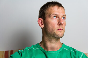Fototapeta premium Portrait of handsome young man looking up in green t-shirt on white background