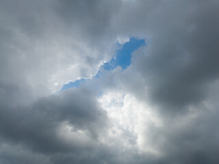 Through the crack in the gloomy clouds, a blue sky can be seen, beautiful clouds of abstract shapes.